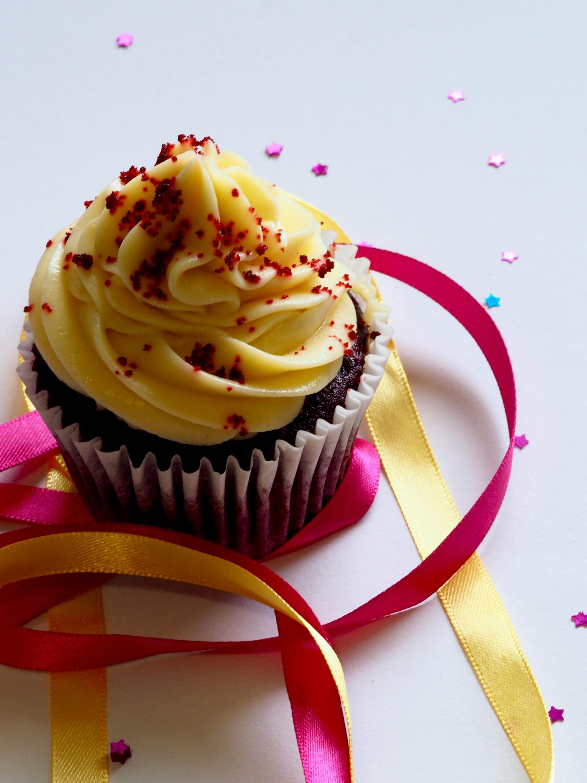 Tempting chocolate cupcake with creamy icing, adorned with colorful ribbons and confetti for a festive celebration.